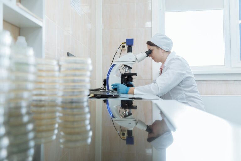 Female scientist using a microscope in a laboratory environment, focusing on research.