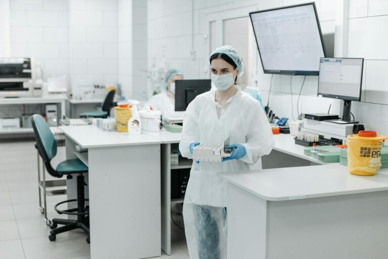 Female scientist wearing PPE working in a modern laboratory with test samples.