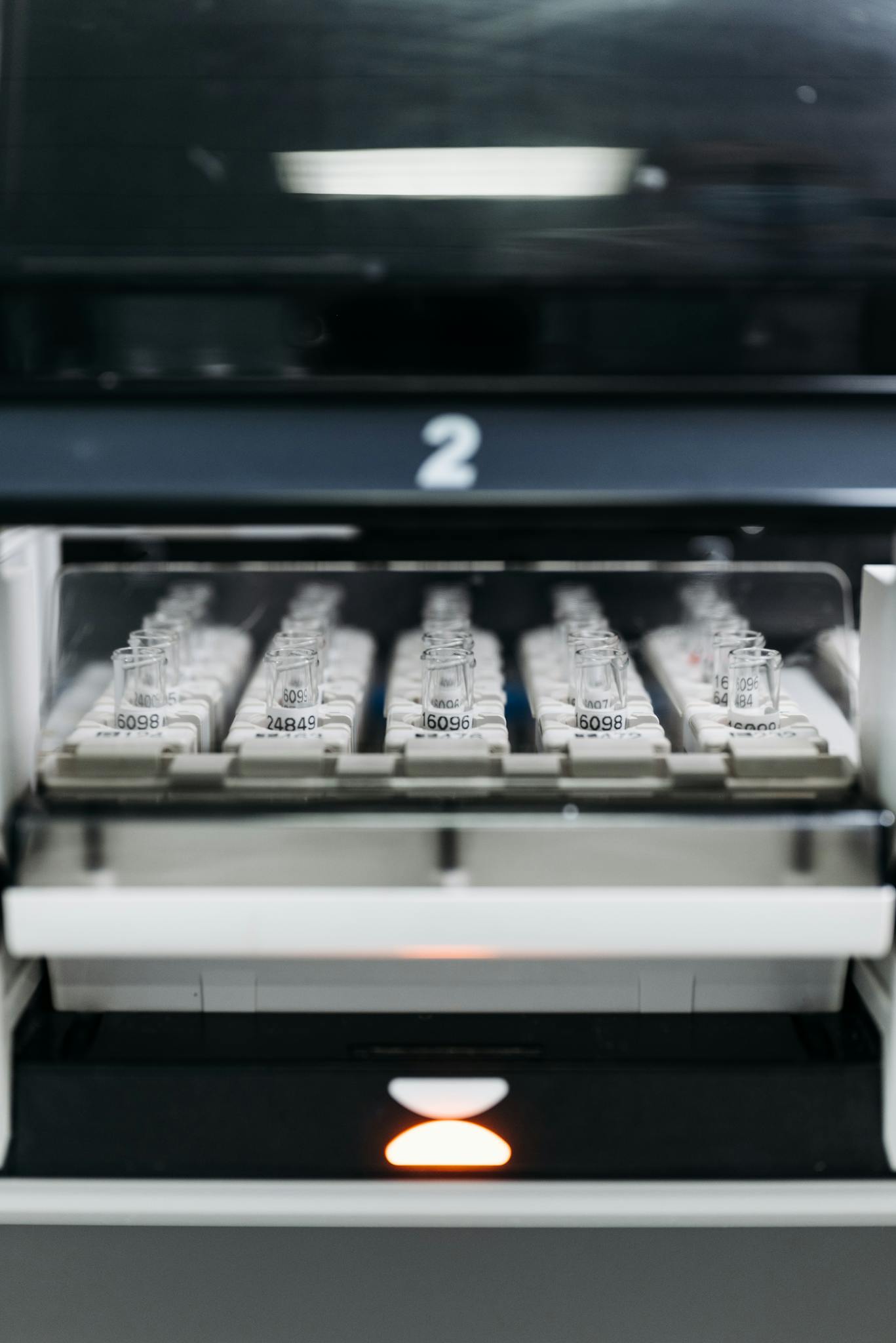 Row of laboratory vials in a scientific machine for analysis and research.